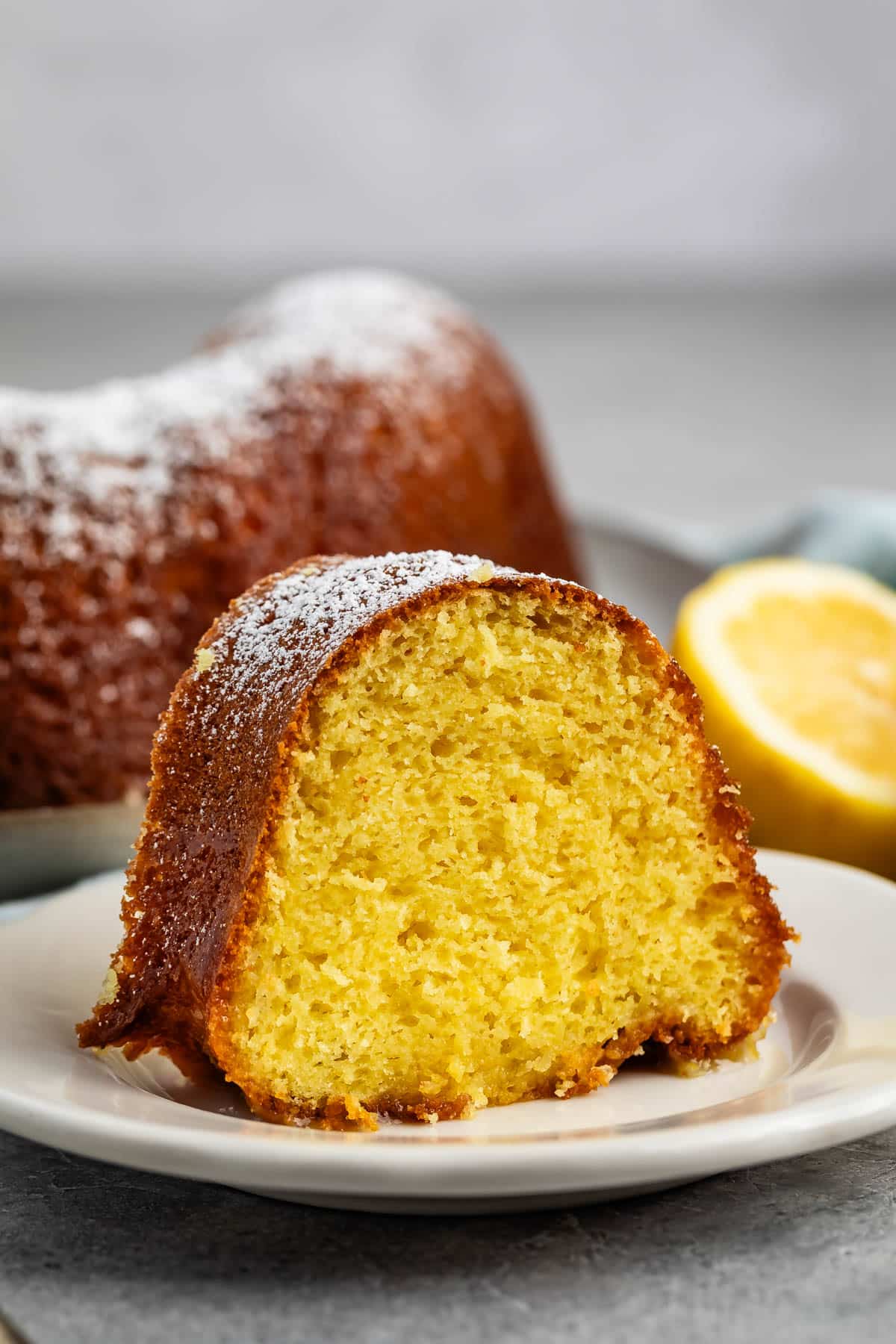 sliced bundt cake on a grey plate covered in powdered sugar.