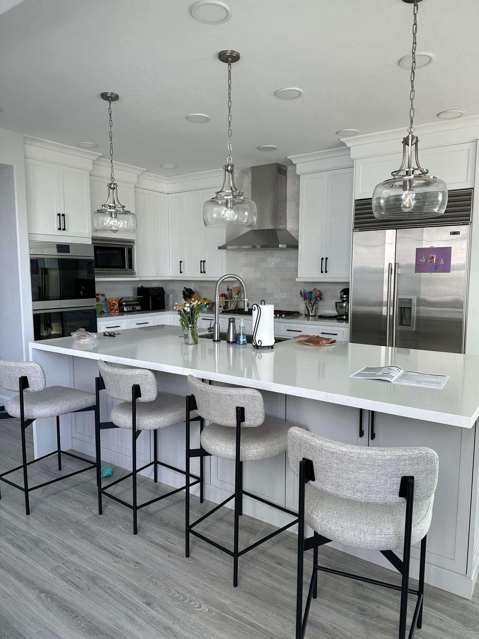 white kitchen with long kitchen island and 4 stools.