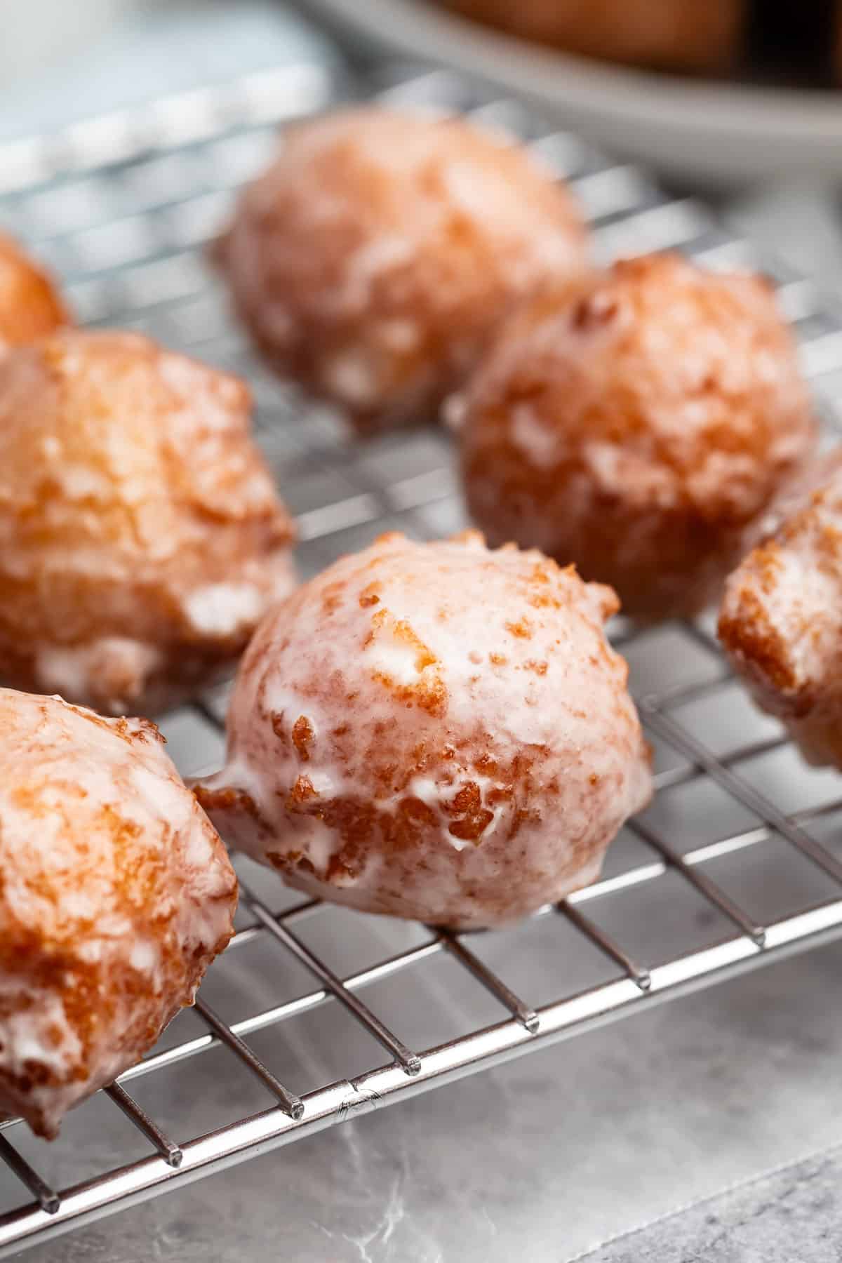 stacked donut holes on a drying rack covered in glaze.