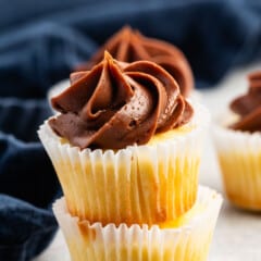 stacked mini vanilla cupcakes with chocolate frosting.