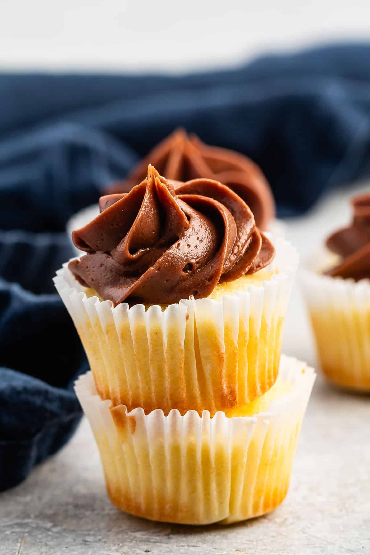 stacked mini vanilla cupcakes with chocolate frosting.