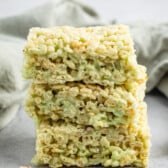 stacked green Rice Krispie treats on a grey table.