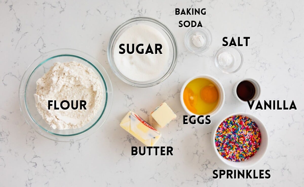 ingredients in sprinkle cookies laid out on a white marble counter.