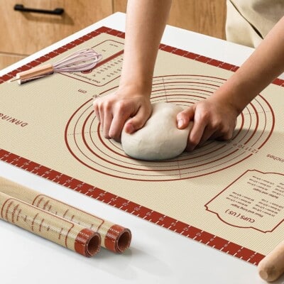 hands kneading dough on mat.