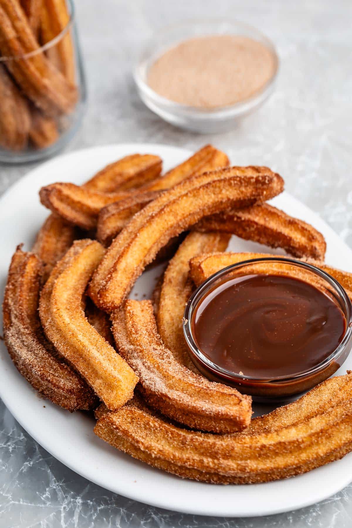 churros placed together on a white plate with a chocolate sauce.