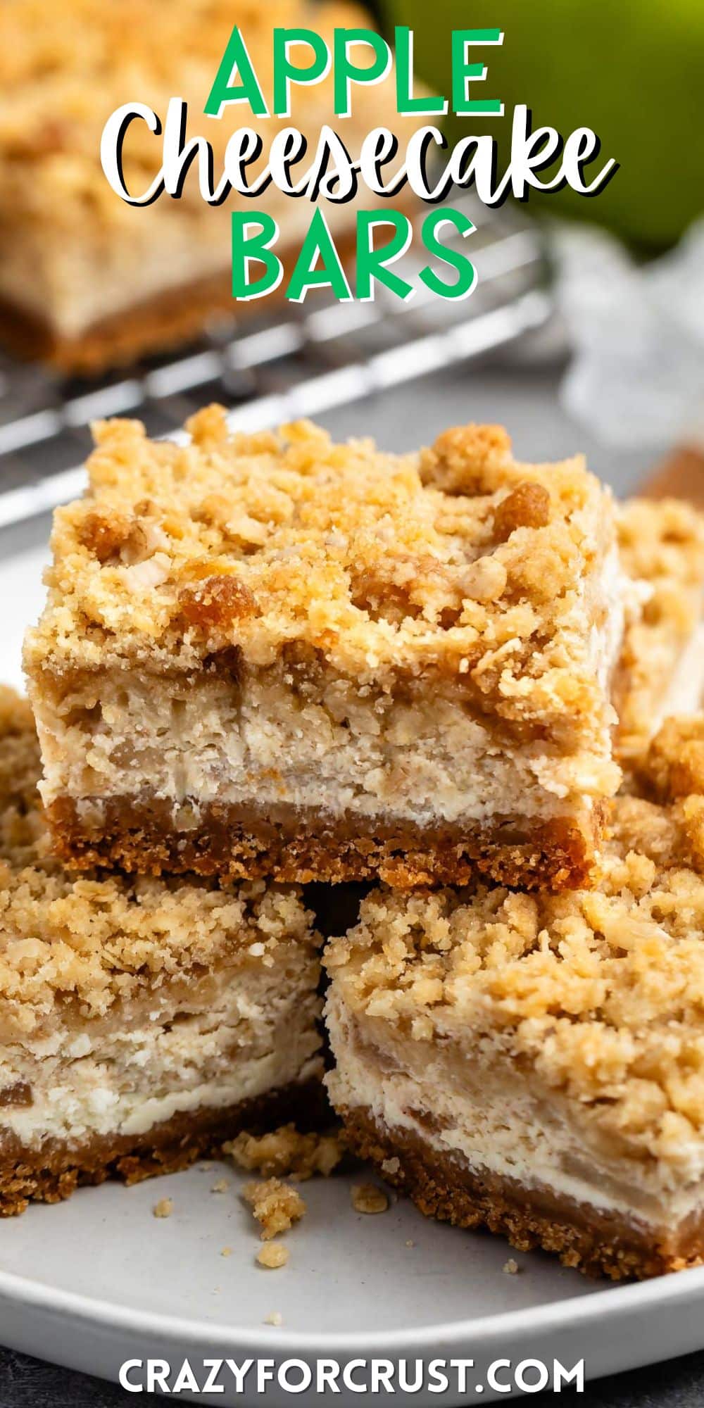 stacked apple cheesecake bars on a grey plate with a crumble topping with words on the image.