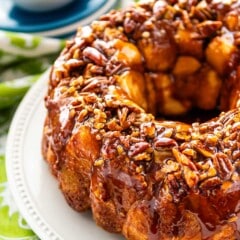 monkey bread on a white plate covered in nuts.