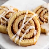 stacked cinnamon roll cookies with a glaze on top.