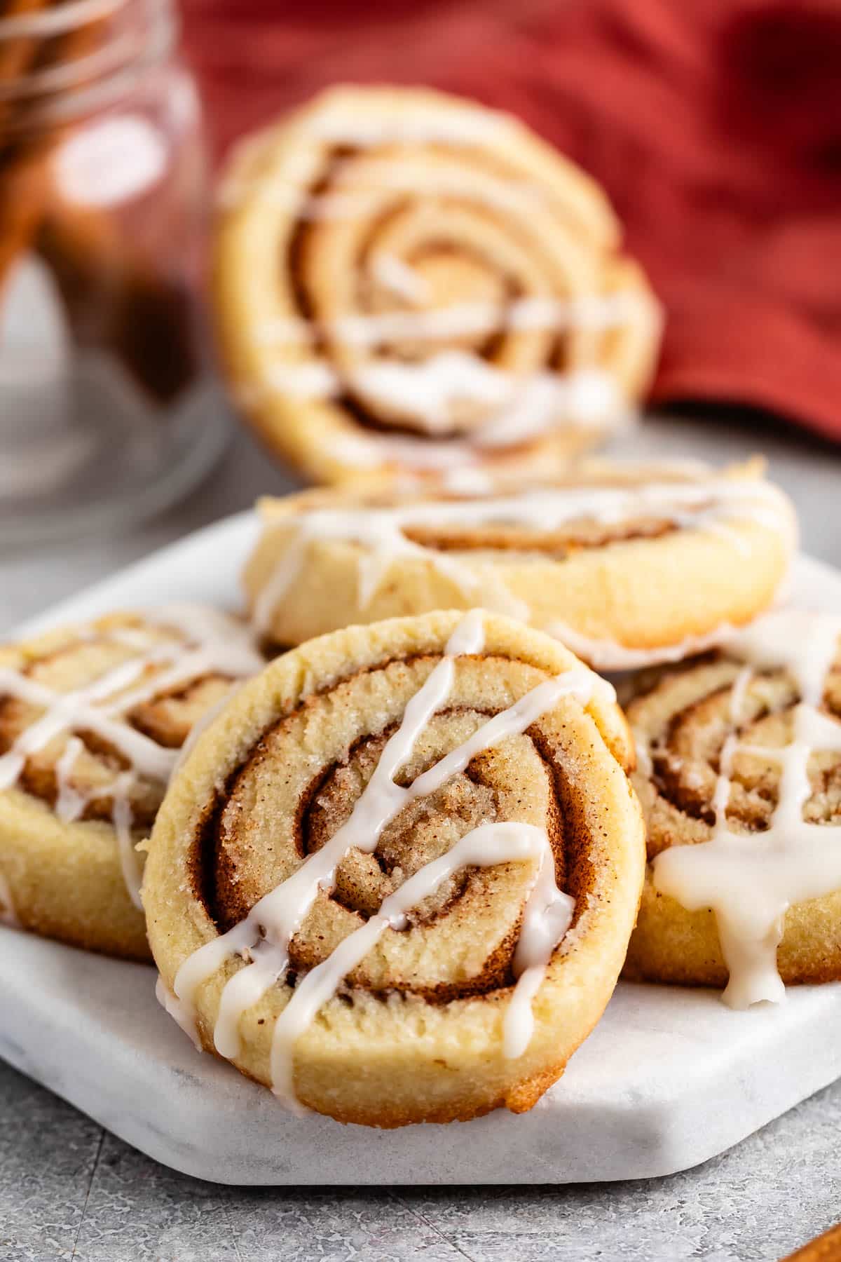 stacked cinnamon roll cookies with a glaze on top.