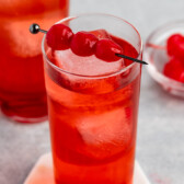 shirley temple in a tall clear glass with cherries along the top.