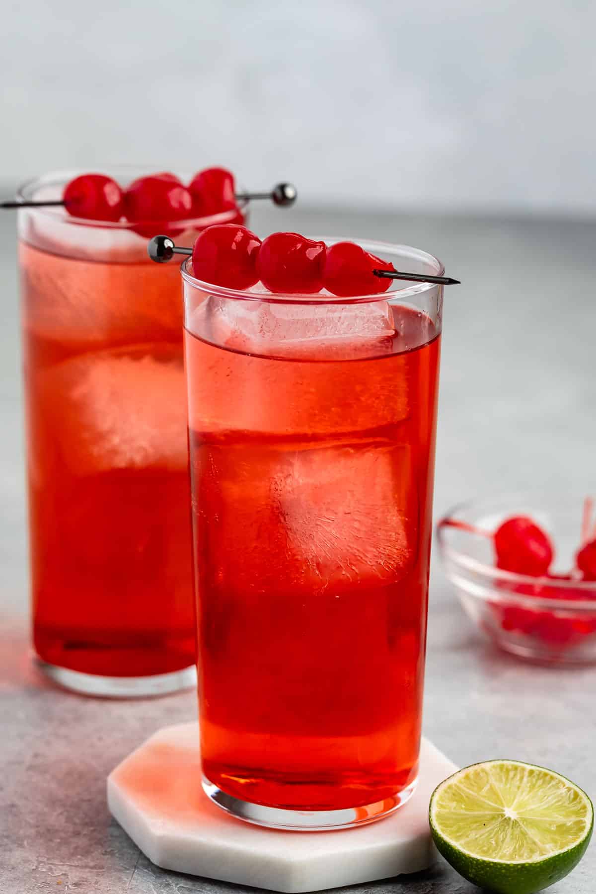 shirley temple in a tall clear glass with cherries along the top.