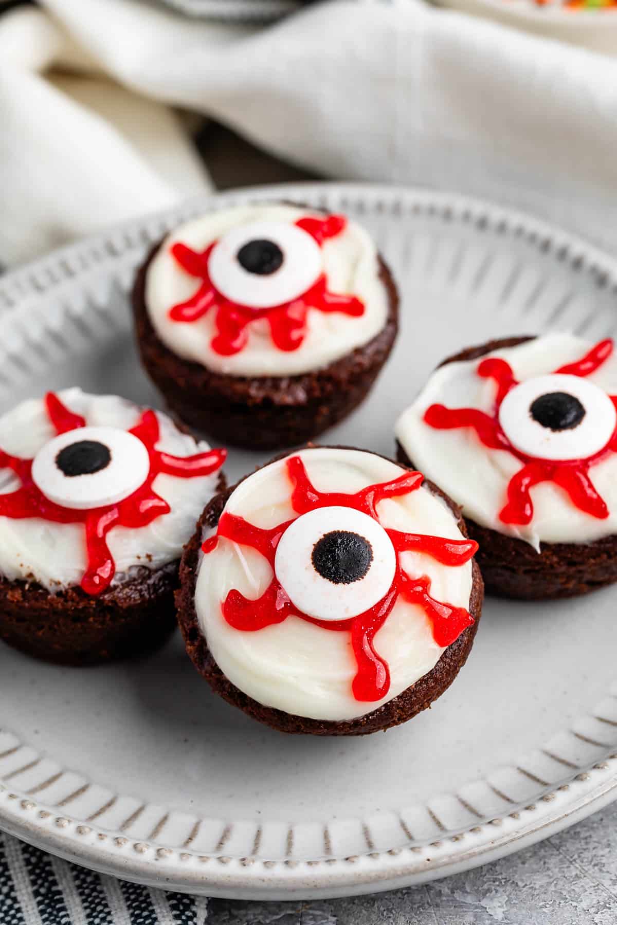 brownies bites with a white frosting, red gel, and candy eyeball on top.