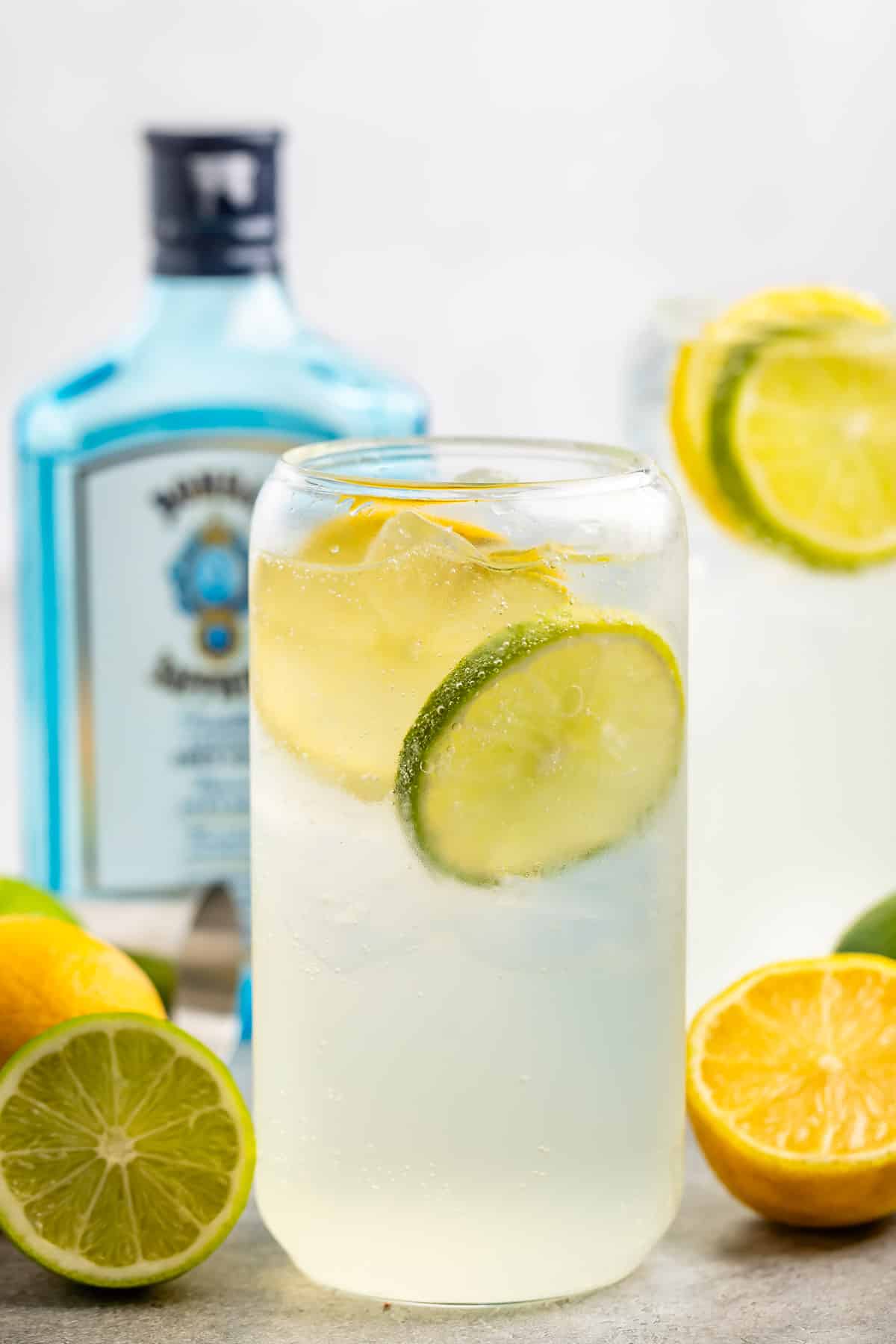 glass cup with clear drink inside and with sliced lemons and limes inside.