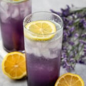 2 tall glasses with purple drink, lemon and lavender behind.