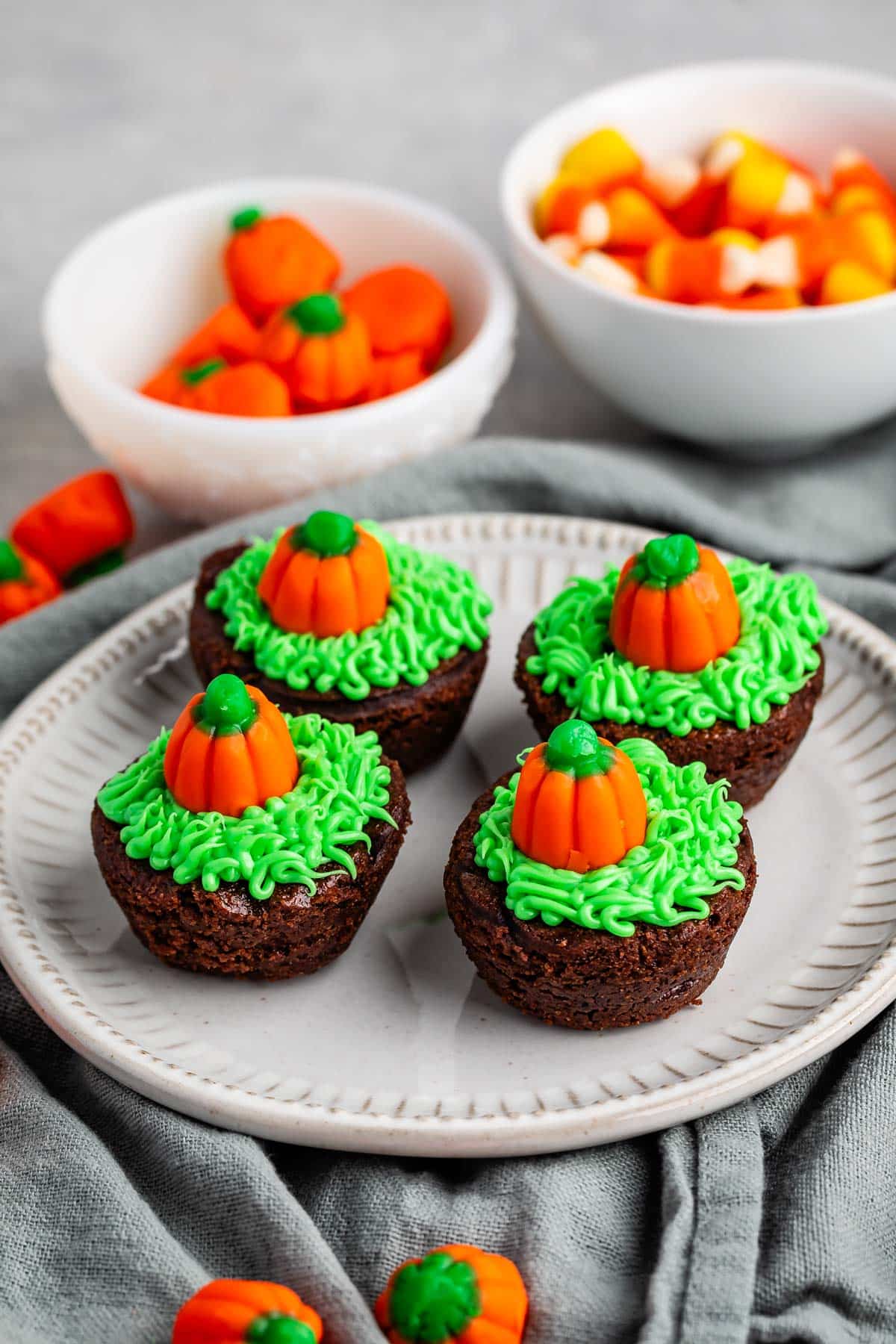 brownie bites topped with green frosting and a pumpkin candy corn.