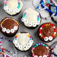 cupcakes with white and chocolate frosting decorated with candy friendship bracelets.