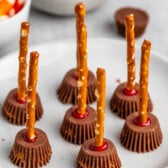 Reeses peanut butter cups with a pretzel stick in the center on a grey plate.