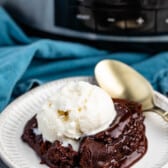 chocolate cake on a white plate with white ice cream on top.