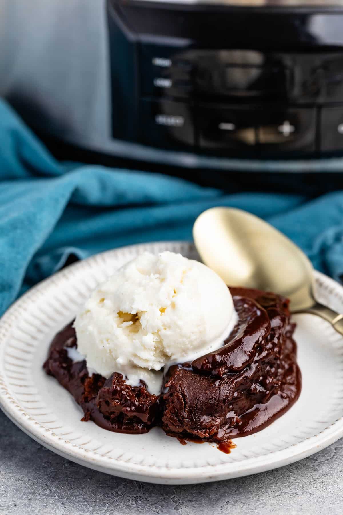 chocolate cake on a white plate with white ice cream on top.