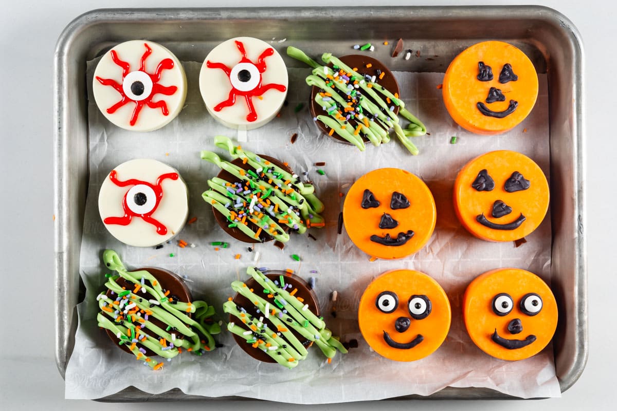 Oreos covered in different colored chocolate forming pumpkins and eyes for halloween.