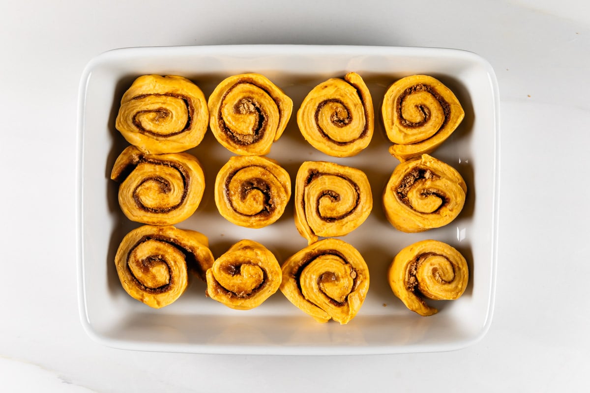 process shot of pumpkin cinnamon rolls being made.