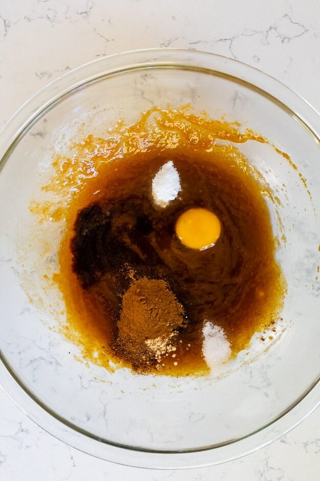 clear glass bowl with pumpkin mixture egg yolk, spices, salt, and baking soda.