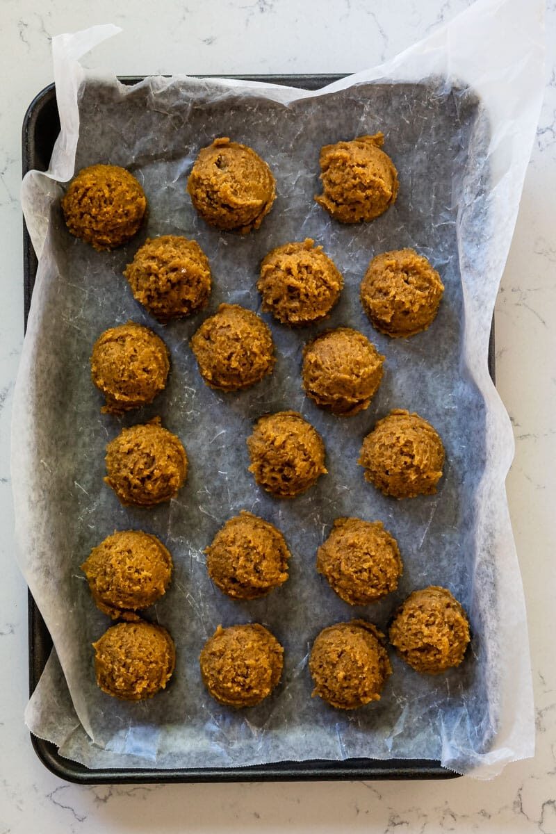 cookie dough balls on cookie sheet lined with parchment.