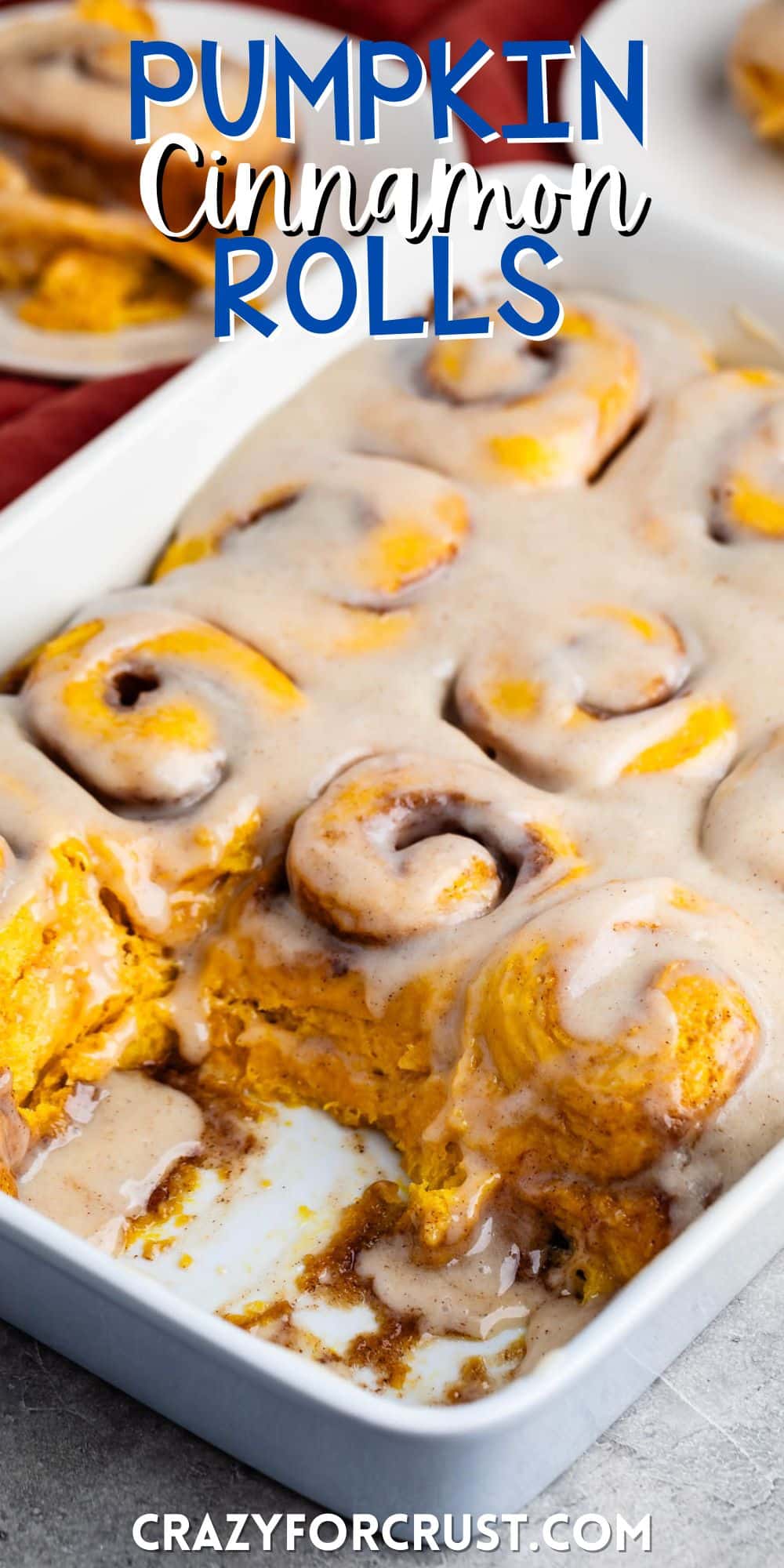 pumpkin cinnamon roll covered in glaze and cinnamon on a white pan with words on the image.