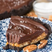 turtle pie next to pecans on a blue and white flower plate.