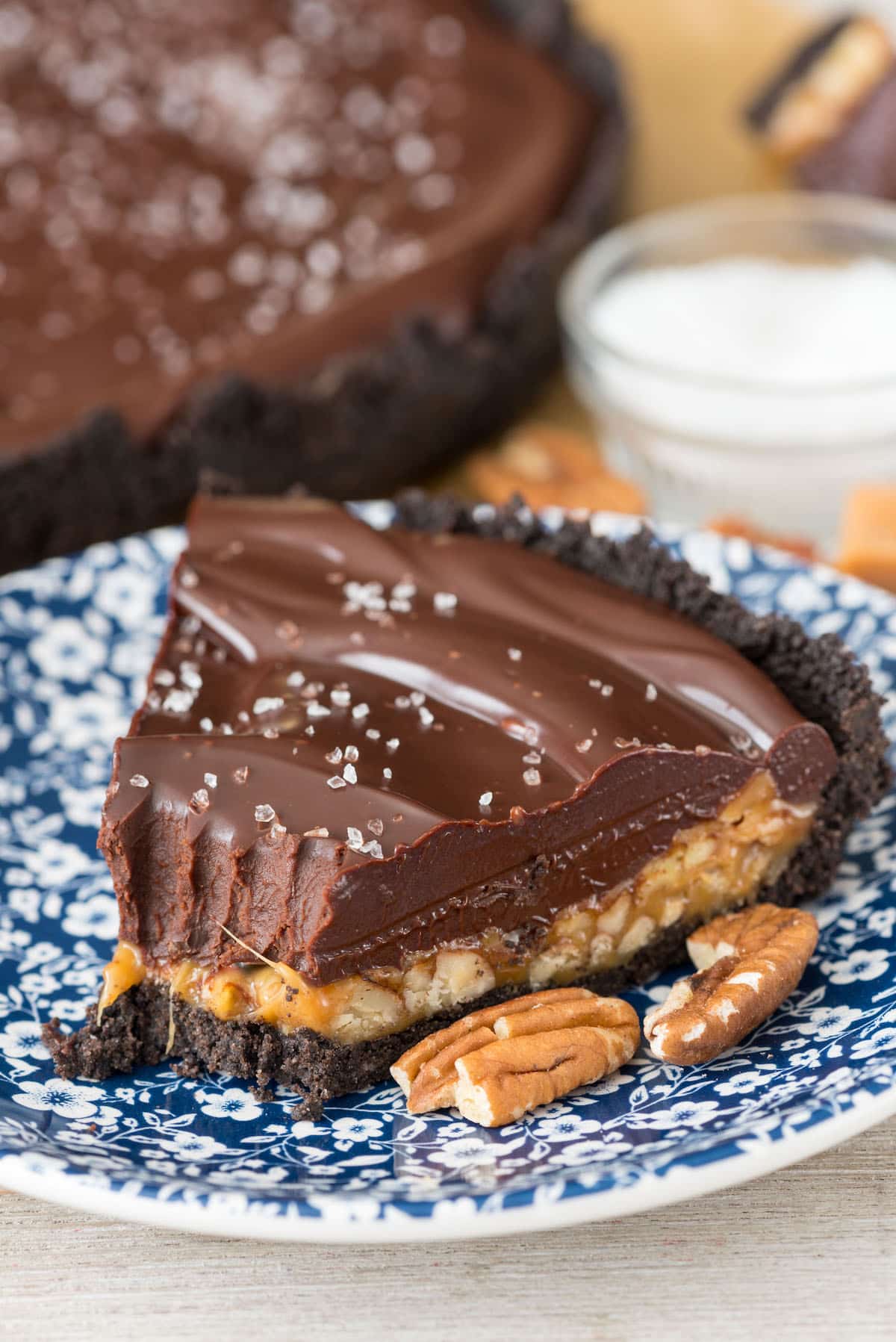 turtle pie next to pecans on a blue and white flower plate.