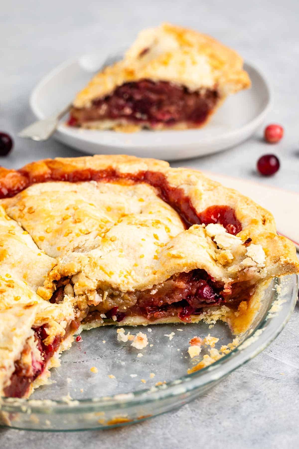 sliced pie with cranberries on the inside in a clear pan.