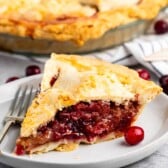 sliced pie with cranberries on the inside on a white plate.