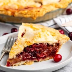 sliced pie with cranberries on the inside on a white plate.