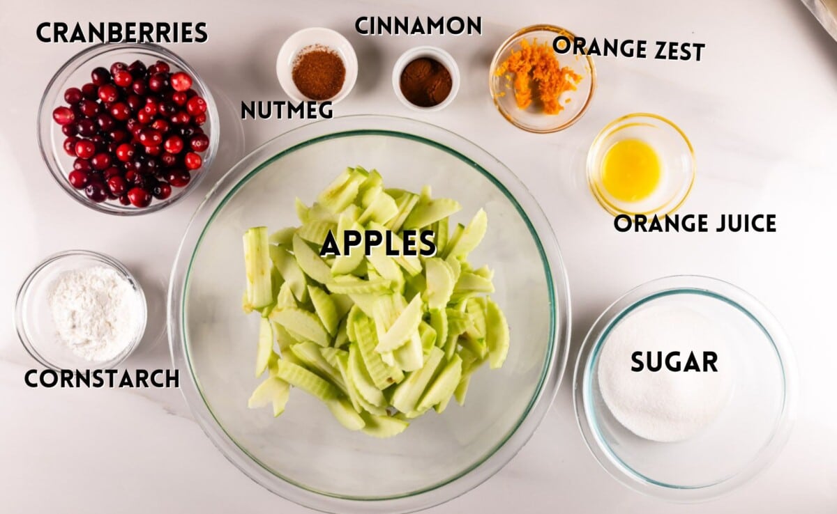 ingredients in apple cranberry pie laid out on a white counter.