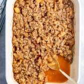 apple crisp in a white dish with a spoon.