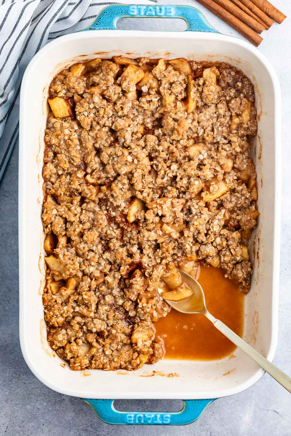 apple crisp in a white dish with a spoon.