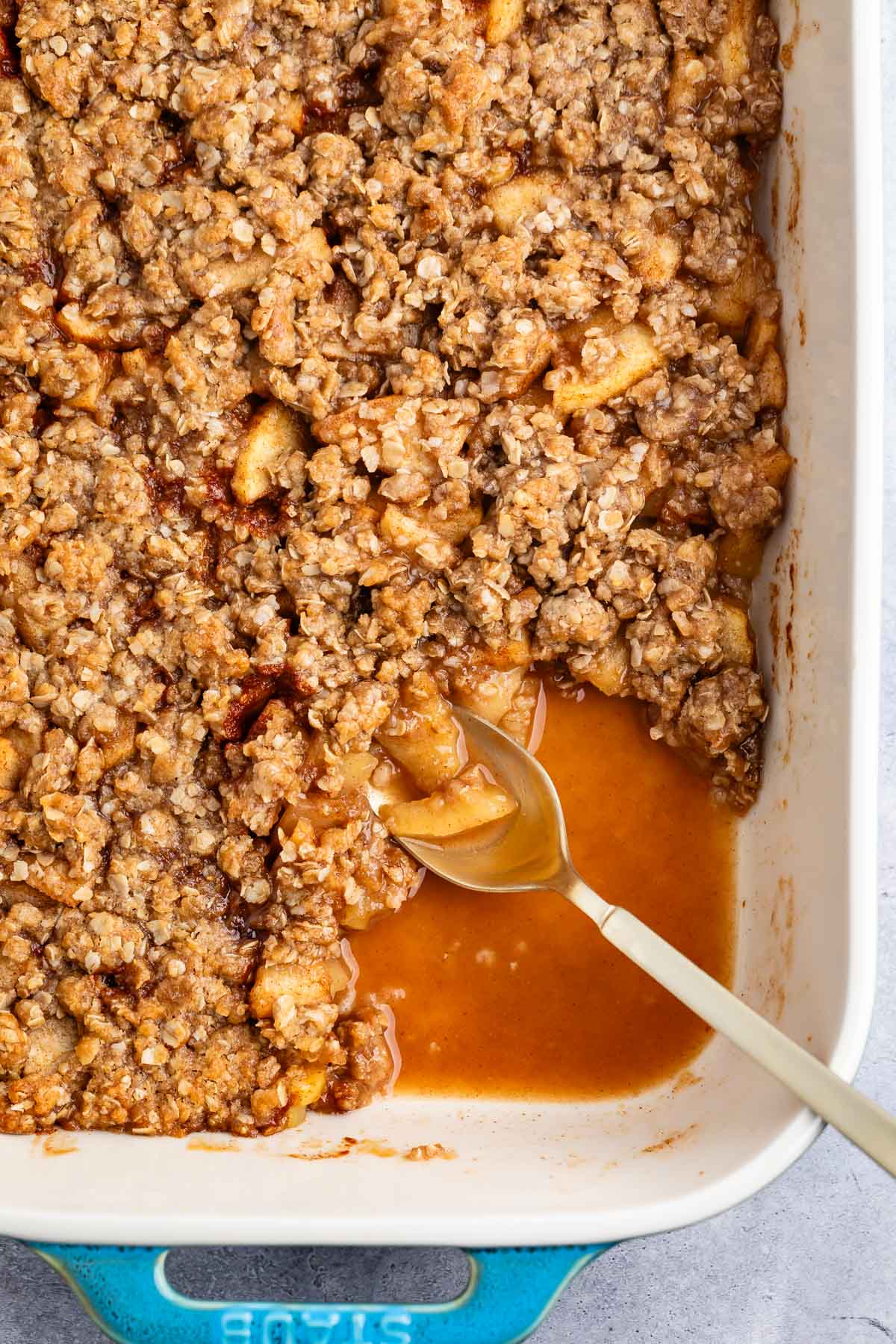 apple crisp in a white dish with a spoon.