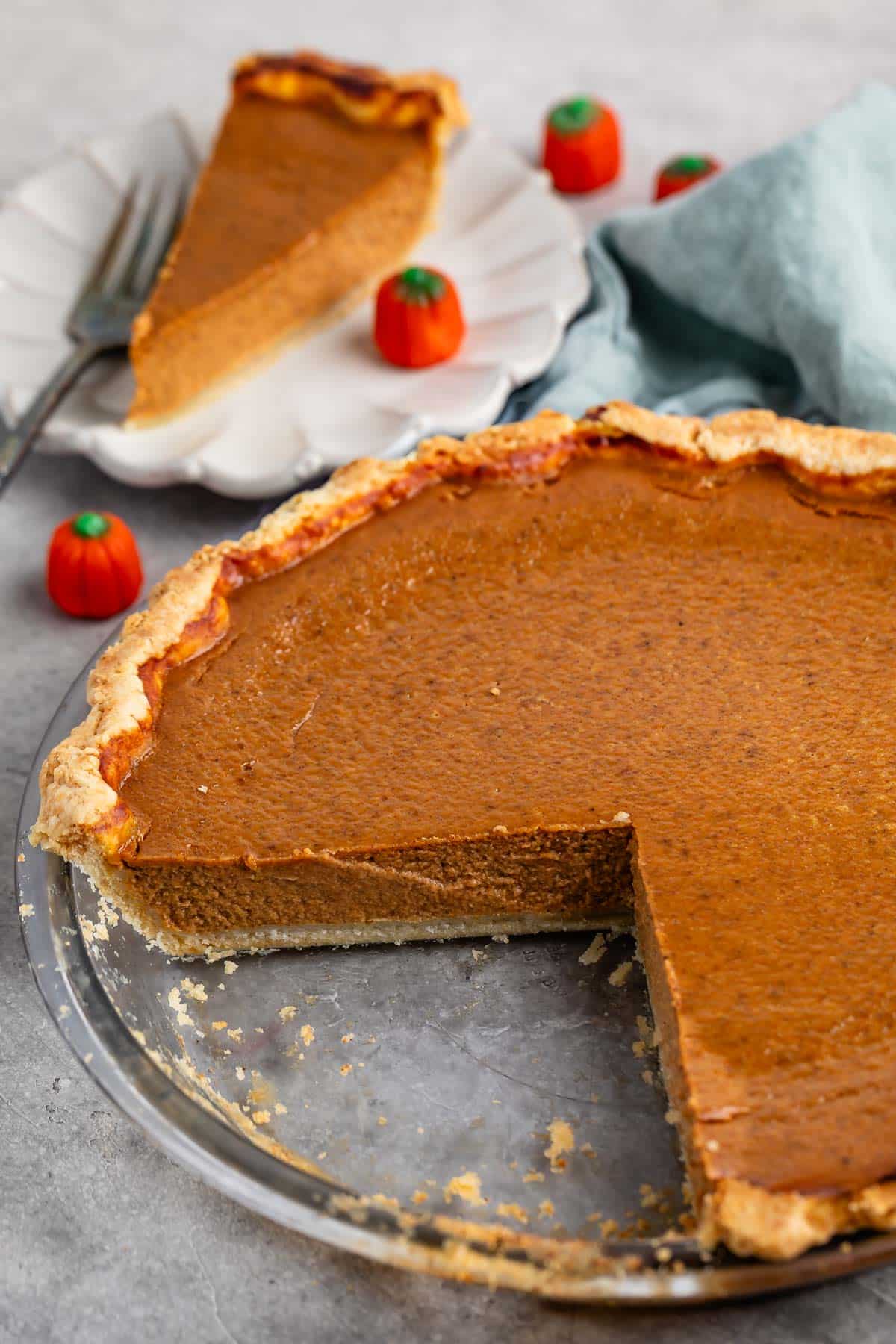 pumpkin pie in a clear pie plate next to a candy corn pumpkin.