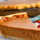 slice of pumpkin pie on a grey plate next to a candy corn pumpkin with words on the image.