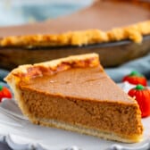 slice of pumpkin pie on a grey plate next to a candy corn pumpkin.