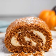 sliced pumpkin cake roll with a white buttercream in the center.