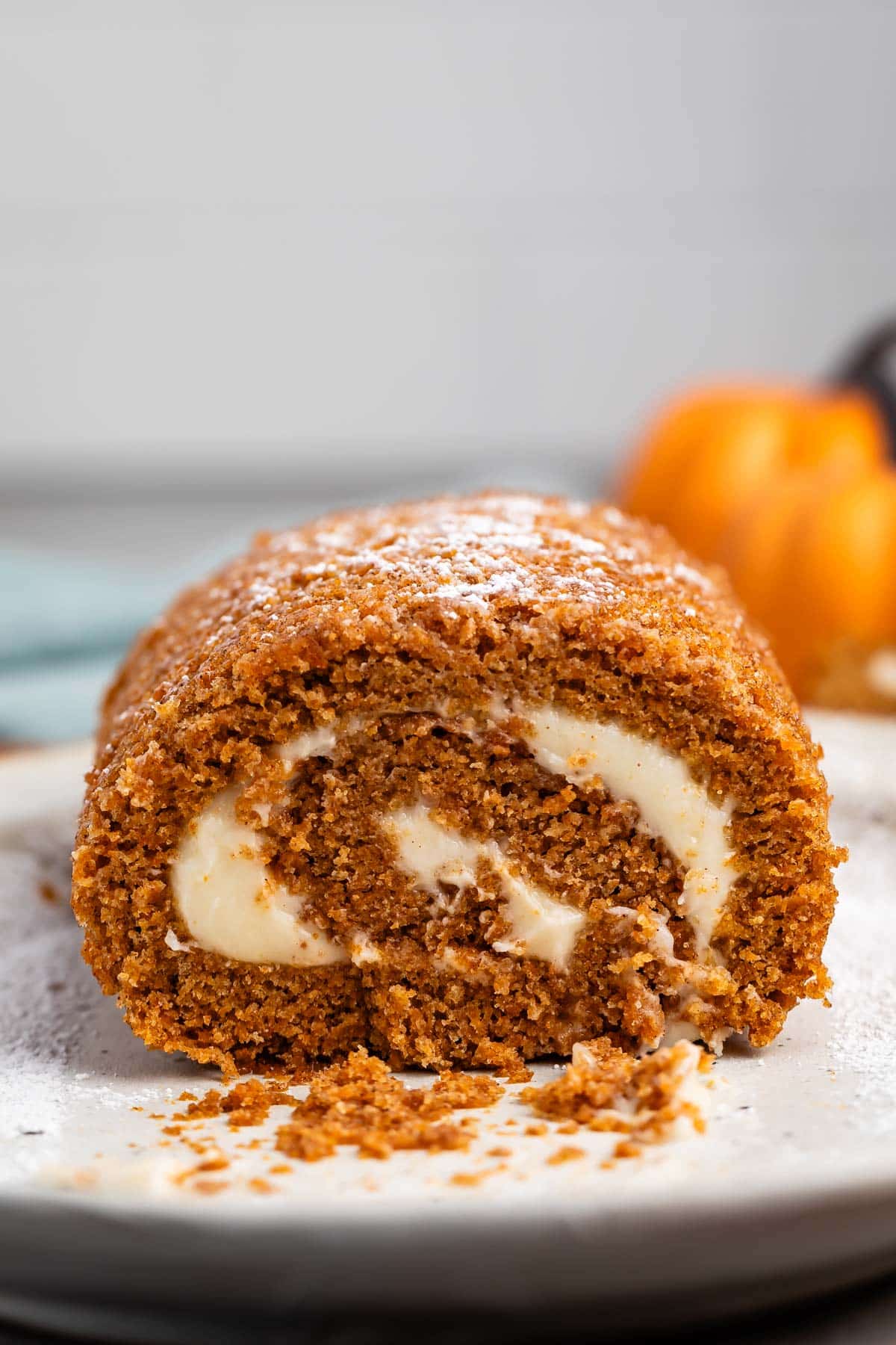 sliced pumpkin cake roll with a white buttercream in the center.