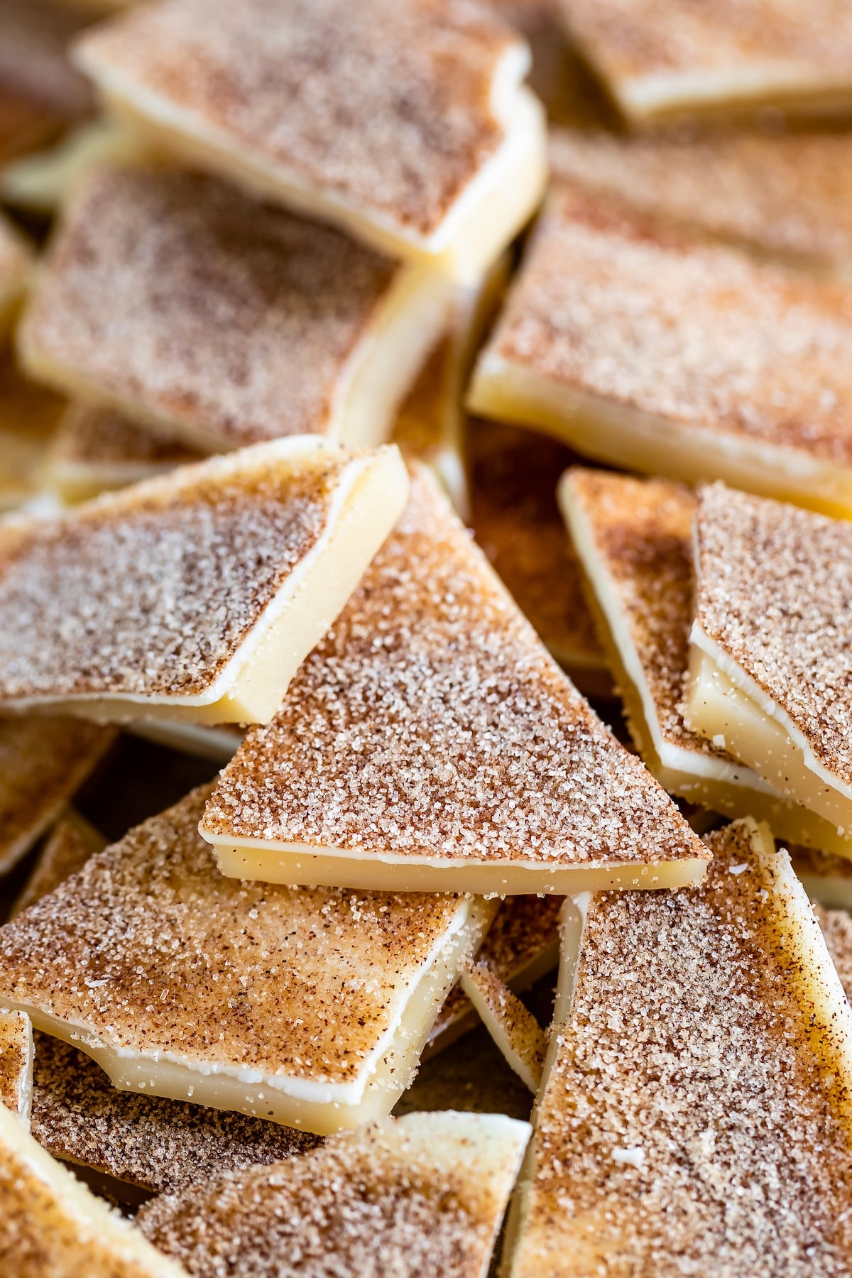 A close-up of crispy cinnamon sugar tortilla chips stacked on top of each other. The chips are golden brown with a dusting of cinnamon and sugar, creating a sweet and crunchy texture.