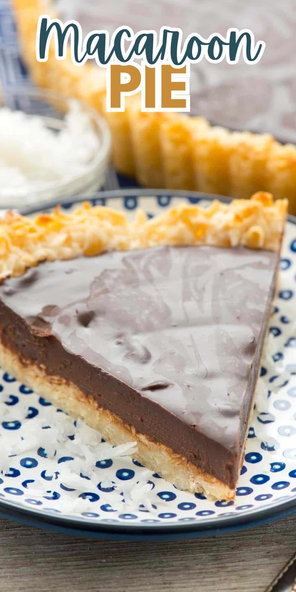 A slice of macaroon pie with a chocolate filling on a blue and white dotted plate. The pie has a textured crust topped with shredded coconut. Another portion of the pie and a bowl of coconut are visible in the background.