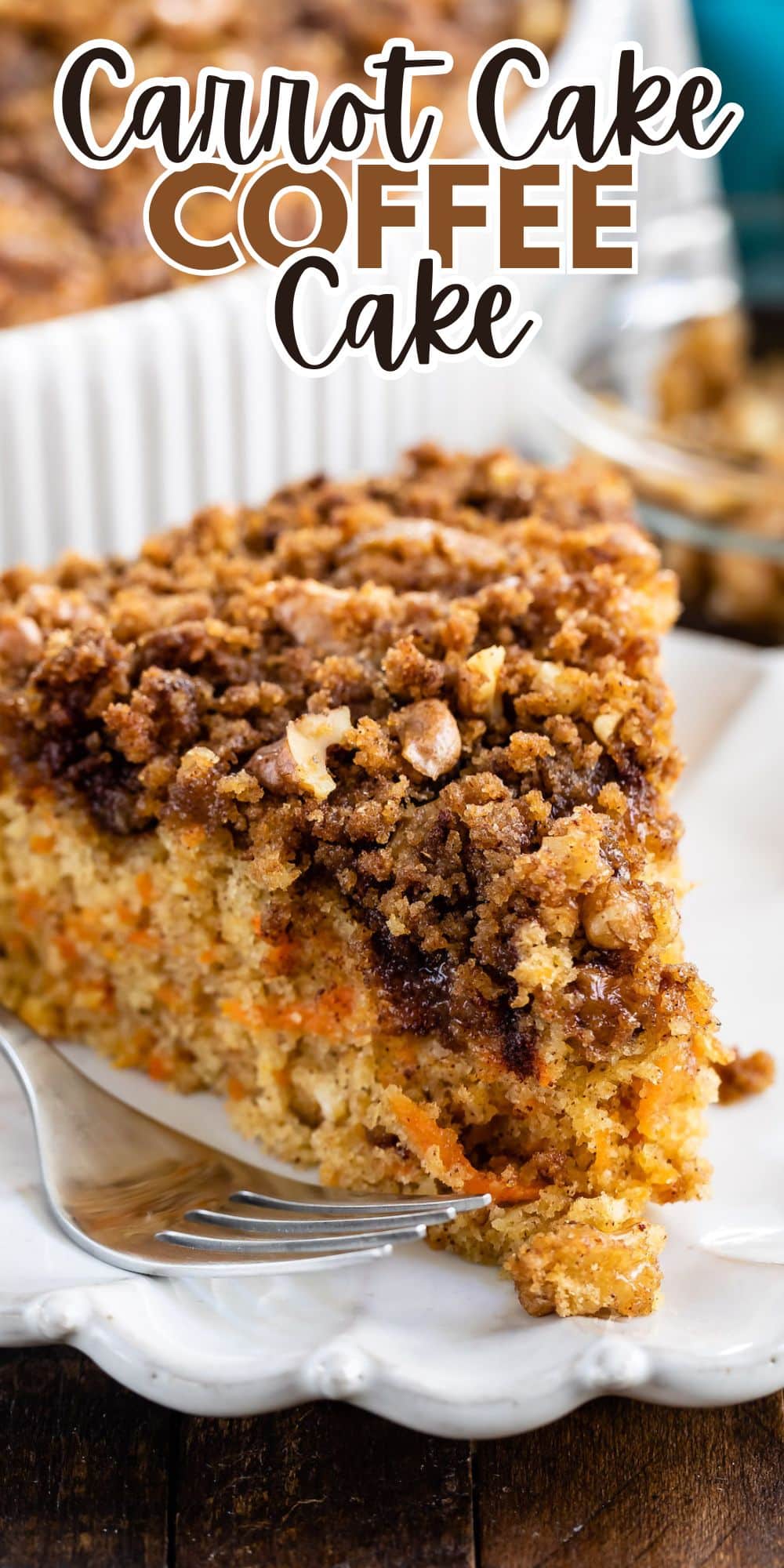 A close-up of a slice of carrot cake coffee cake on a white plate. The cake is topped with a crumbly streusel and visible bits of carrot. A fork rests beside the slice. The text Carrot Cake Coffee Cake is displayed above.