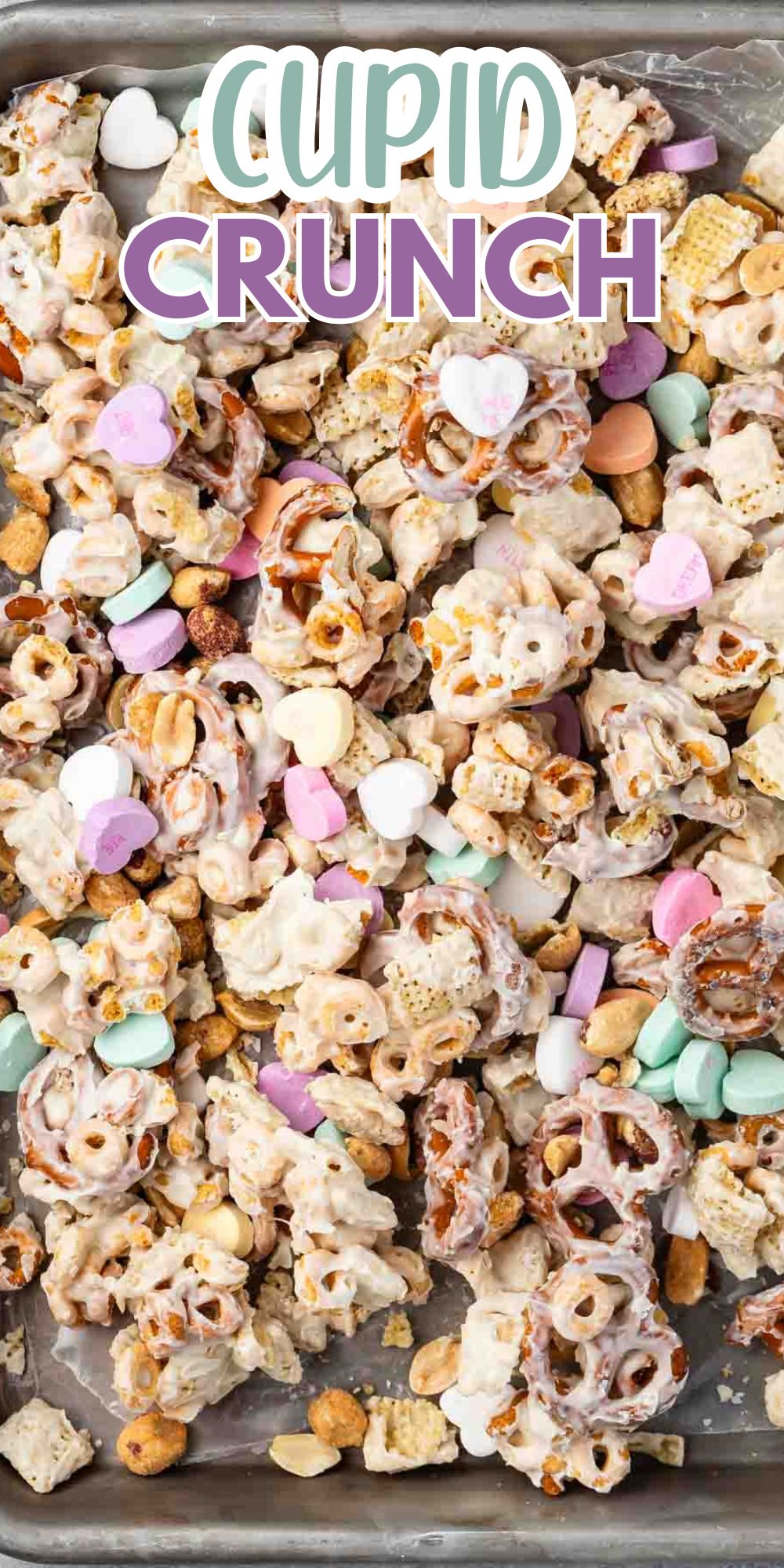 A mix of pretzels, cereal, peanuts, and colorful candy hearts coated in a light glaze, spread out on a baking sheet. Text on the image reads Cupid Crunch.