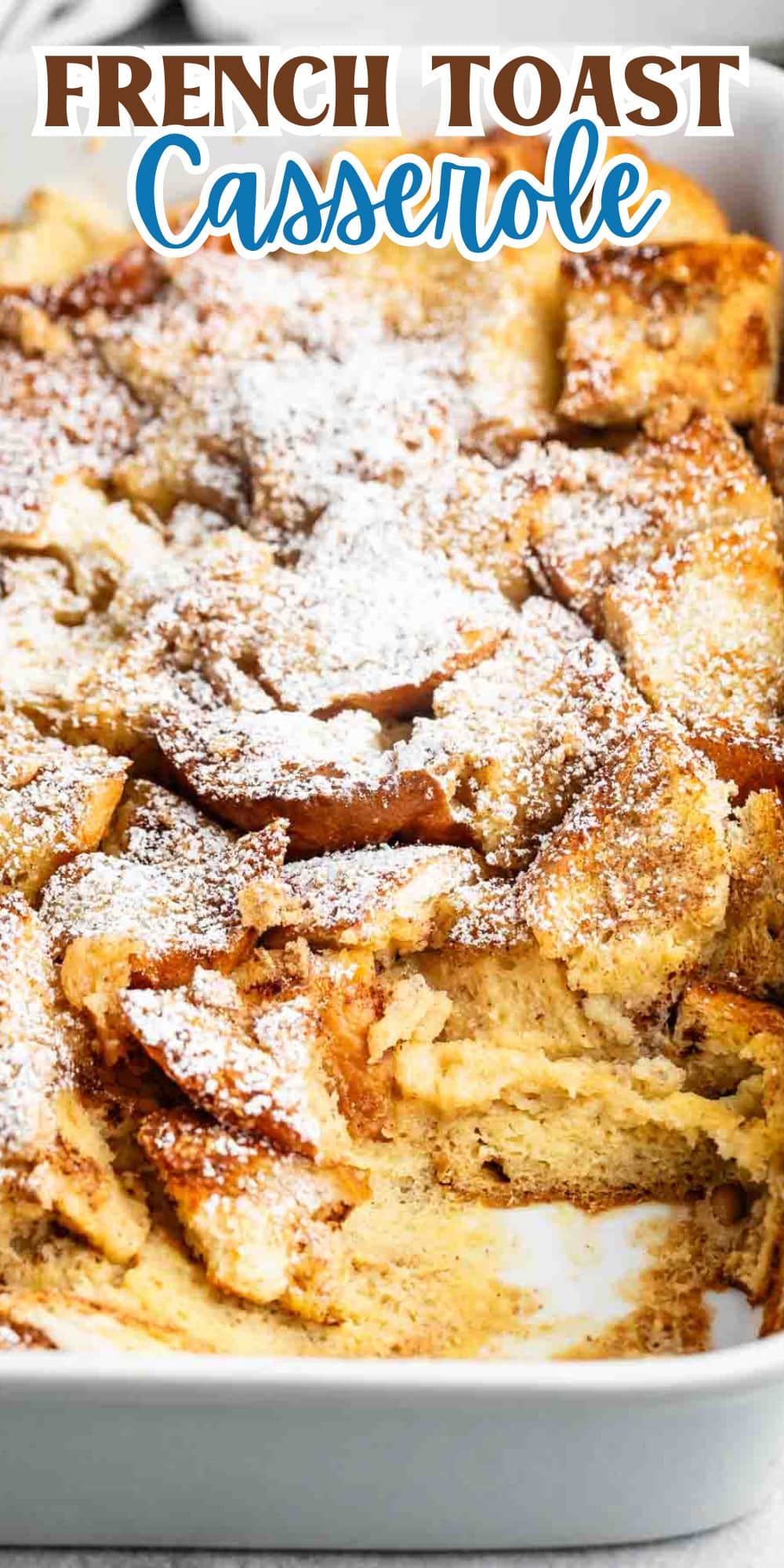 A close-up of a French toast casserole in a white baking dish, topped with powdered sugar. The casserole is golden brown and has a fluffy texture. The text above reads French Toast Casserole in blue and orange lettering.