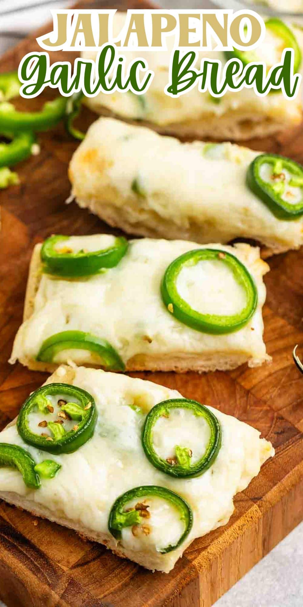 Four slices of jalapeño garlic bread topped with melted cheese and jalapeño slices are arranged on a wooden cutting board.