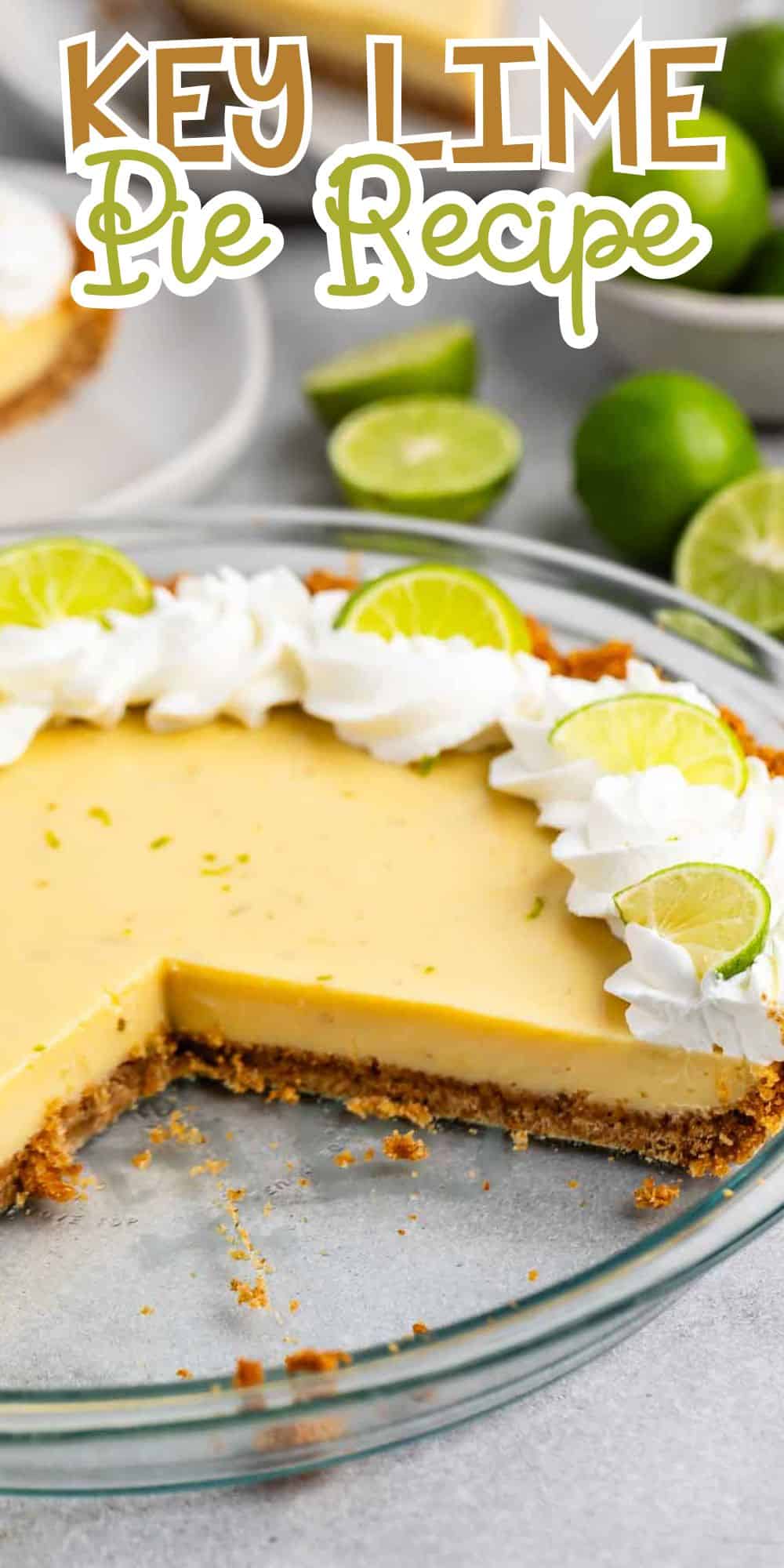 A key lime pie with a slice removed, revealing a creamy yellow filling and a crumbly crust. Topped with whipped cream and lime slices, surrounded by whole limes in the background. Decorative text at the top reads Key Lime Pie Recipe.